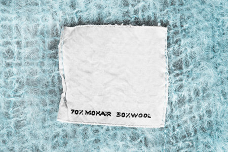 Composition textile clothes label on blue wool background closeup