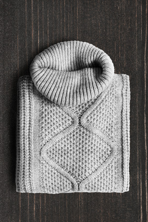 Folded grey wool sweater on dark wooden backgroundの写真素材