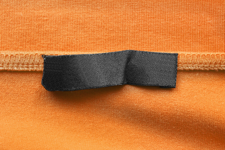 Blank black clothes label on yellow textile backgroundの写真素材