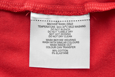 Care and composition clothes label on red textile background closeupの写真素材