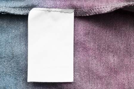 Blank white clothes label on colorful textile background closeupの写真素材