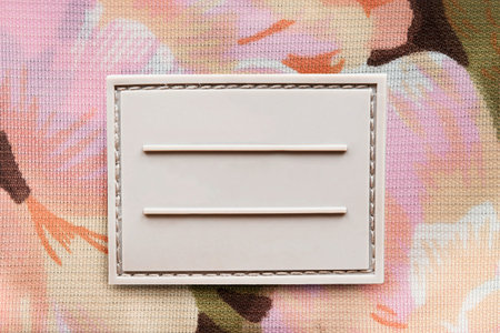 Blank rubber clothes label on colorful textile background closeup