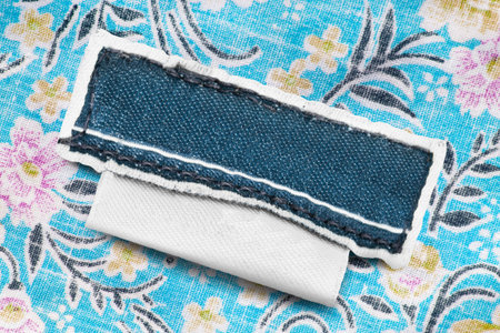 Blank textile clothes label on colorful cotton background closeup