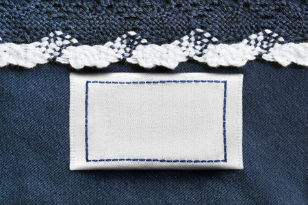 Blank white clothes label on blue textile background closeup