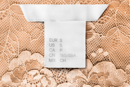 S size clothes label on yellow lacy background closeup
