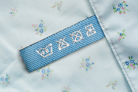 Care clothes label on blue floral textile background closeup