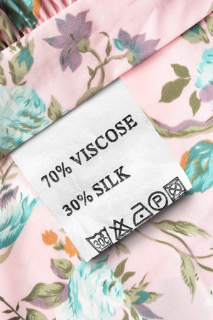 Composition and care clothes label on pink floral textile background