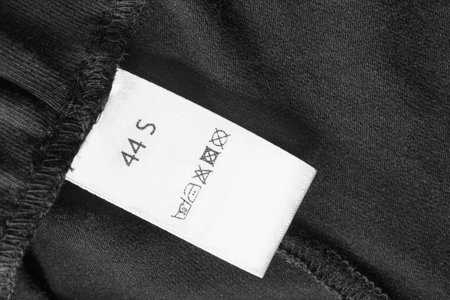 Small size and care clothes label on black textile background