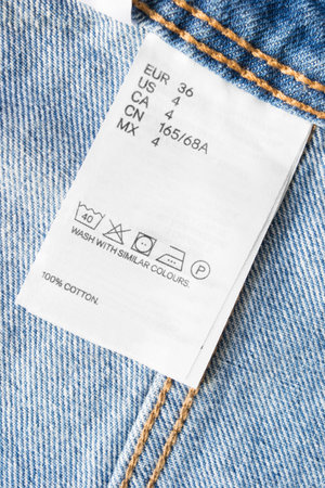 36 size care and composition clothes label on blue denim background