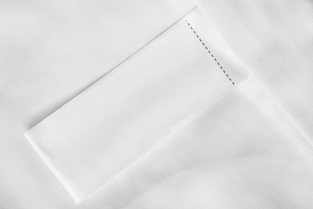 Blank clothes label on white textile background closeup