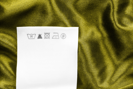 Care clothes label on yellow satin background closeupの写真素材