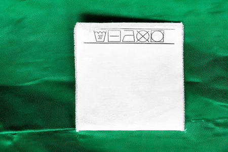 Care clothes label on green textile background closeup