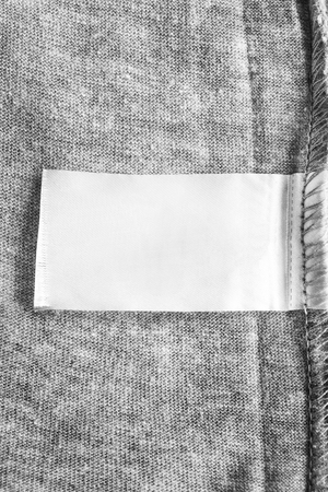 Blank white clothes label on grey knitted backgroundの写真素材