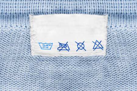 Care clothes label on blue knitted background closeup
