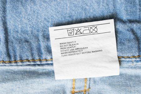 Care clothes label on blue denim background closeup