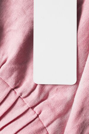 Blank white clothes label on pink linen background closeupの写真素材