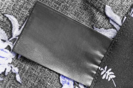 Blank black clothes label on textile background closeupの写真素材
