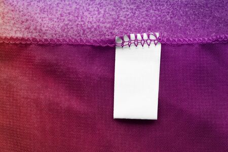 Blank clothes label on colorful red and purple textile backgroundの写真素材