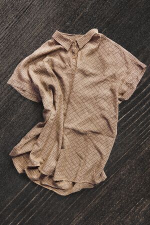Yellow silk crumpled shirt on dark brown wooden backgroundの写真素材