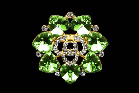Gold brooch with emeralds and diamonds on black backgroundの写真素材