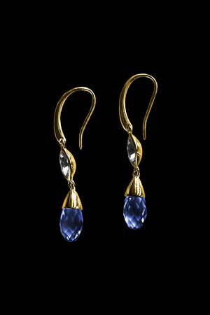 Elegant gold earrings with blue crystals isolated over blackの写真素材