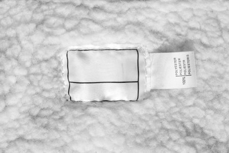 Clothes label says 100% polyester on white textile background