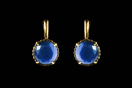 Elegant gold earrings with large blue gems on black backgroundの写真素材