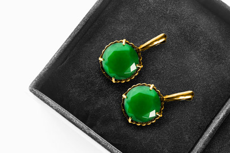 Pair of elegant emerald gold earrings in black jewel box closeup