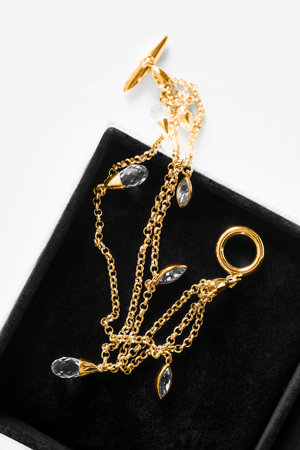 Gold chain bracelet with crystal pendants in black jewel box closeup