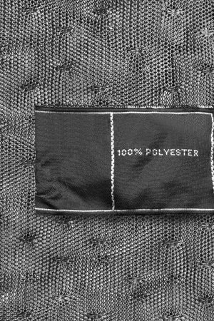 Clothes label says 100% polyester on black lacy background closeup