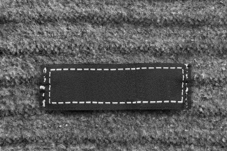 Blank textile clothes label on black knitted wool background