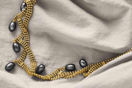 Elegant black pearl gold necklace on beige draped linen closeupの写真素材