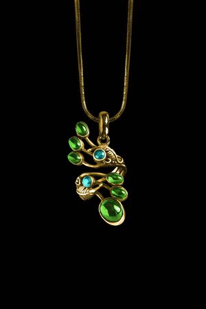 Vintage beautiful gold pendant with emeralds and topaz hanging on a chain on black backgroundの写真素材