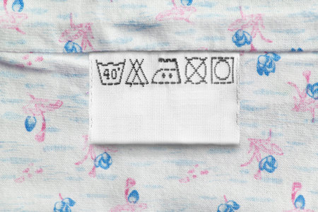 Care clothes label on blue floral textile background closeup