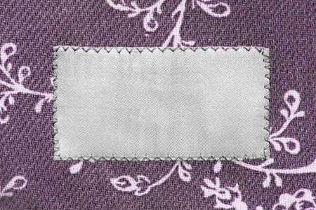 Blank textile patch on purple cotton background closeup