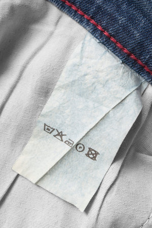 Care clothes label on cotton denim background closeup