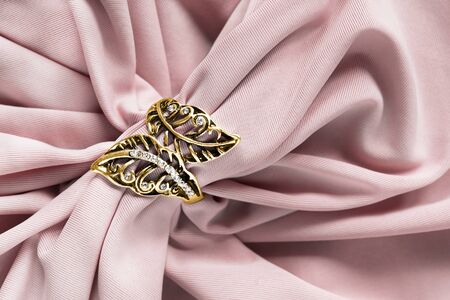 Carved gold ring with crystals on draped rose silk closeupの写真素材