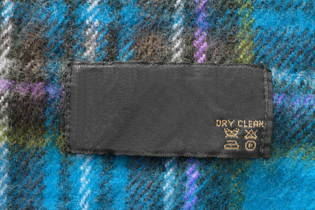 Care clothes label on blue plaid wool background closeup