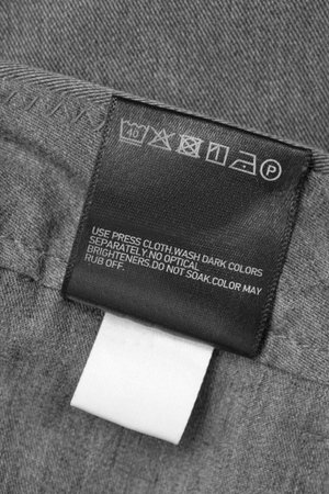 Care clothes label on grey textile background closeup