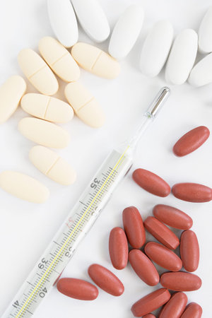 Lot of medical pills and a thermometer closeup on white background