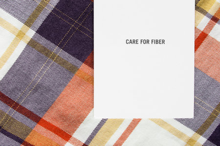 Clothing label says care for fiber on colorful tartan background closeup