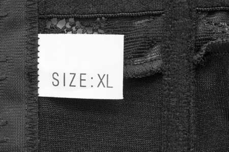 Size XL clothing label on black textile backgroundの写真素材
