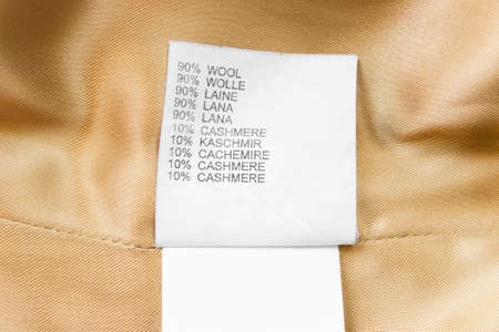 Fabric composition clothing label in different languages on golden textile backgroundの写真素材