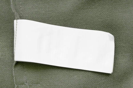 Blank white clothing label on khaki green textile background