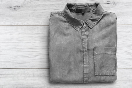Folded basic gray denim shirt on white wooden background