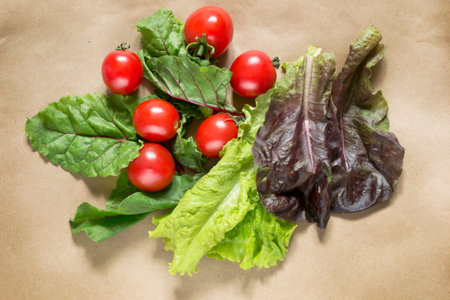 Group of cherry tomatoes and leaf lettuce on craft paper backgroundの写真素材