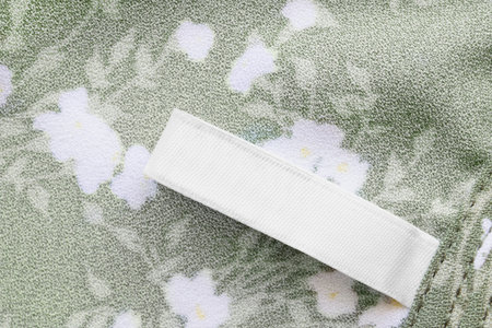 Blank clothing label on green textile background