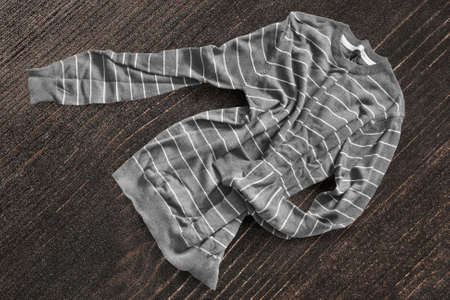 Crumpled gray striped knitted pullover on dark brown wooden backgroundの写真素材