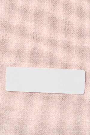 Blank white clothing label on pink textile background