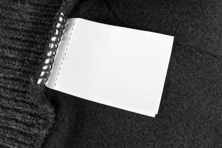 Blank white clothing label on black wool background